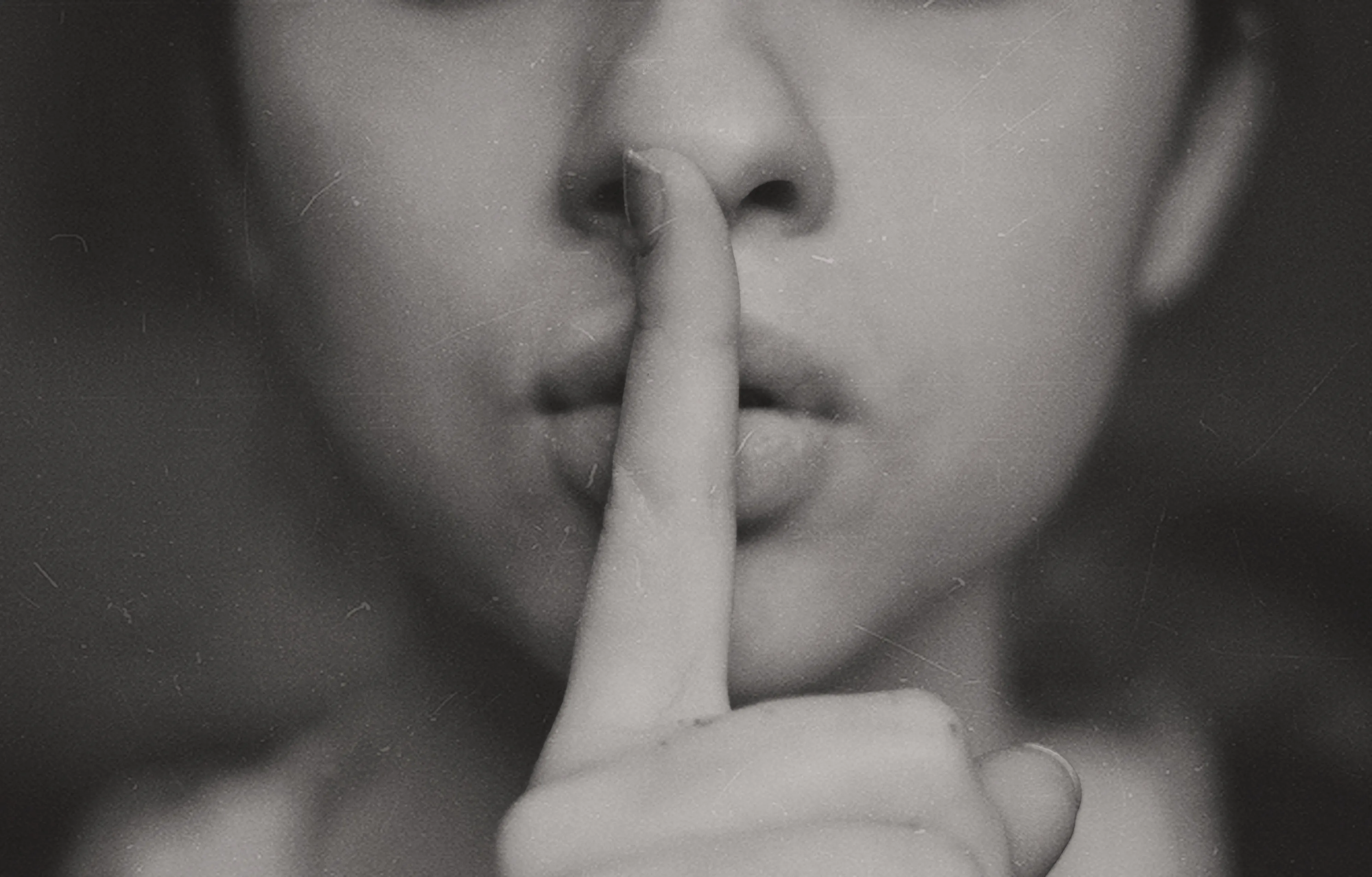 Old looking black and white photo of person making shush motion